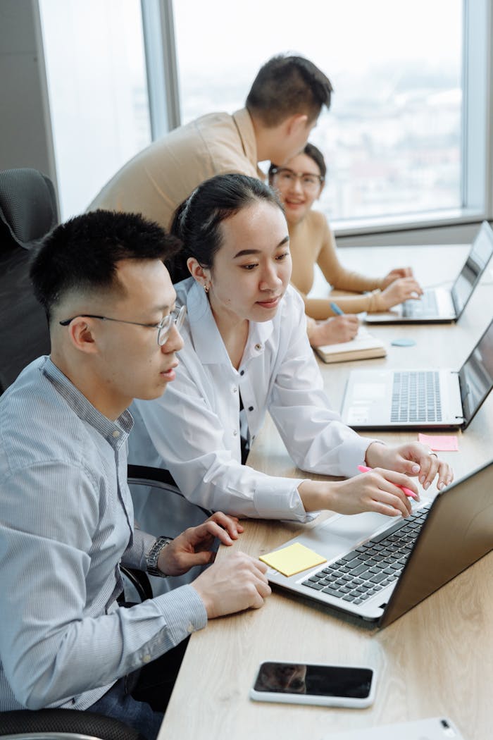 Young professionals collaborating on laptops in a modern office setting.